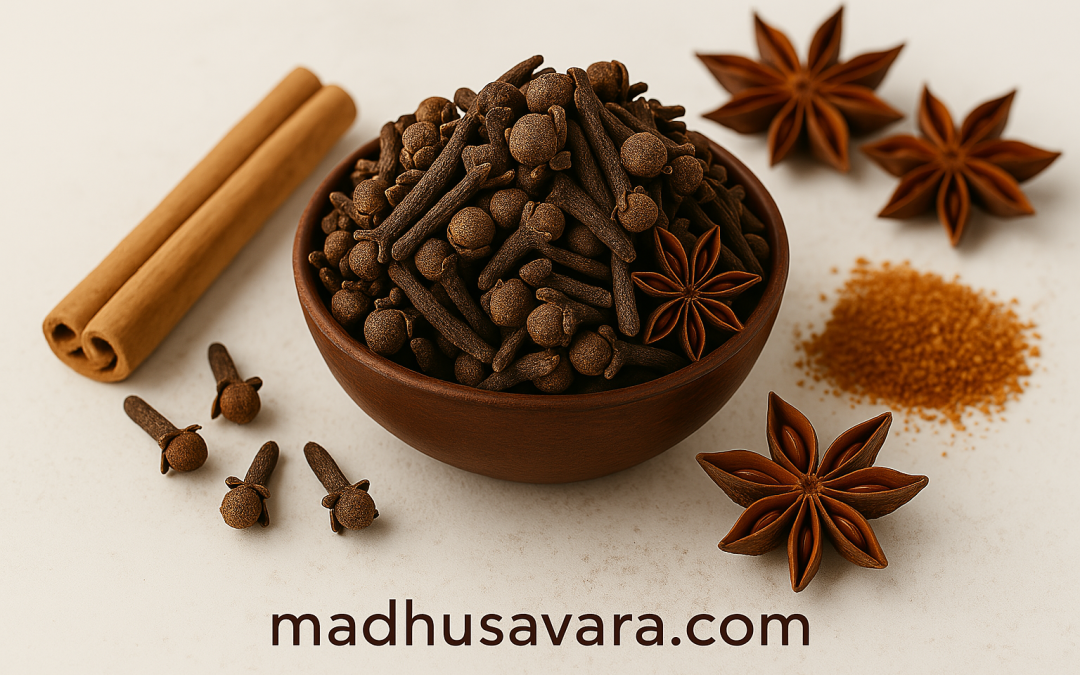 Flat lay of cloves prominently displayed among cinnamon sticks, green cardamom, star anise, and peppercorns on a light background