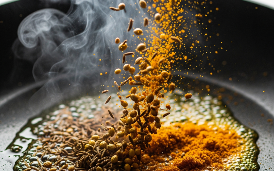 Close-up of jeera (cumin) seeds and other Indian spices sizzling in a tarka pan, with steam rising against a clean white background.