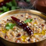 Authentic Mash ki Dal Recipe in traditional brass bowl, creamy Kangra style black gram dal from Himachal Pradesh, garnished with fresh coriander, dry red chilli, cumin seeds and ghee, traditional Kangri Dham food by Madhu Savara
