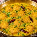 Authentic Boor ki Kadi served in a traditional brass bowl, featuring soft besan boor dumplings in tangy Himachali yogurt gravy, garnished with coriander leaves and whole red chillies, a classic Kangri Dham delicacy