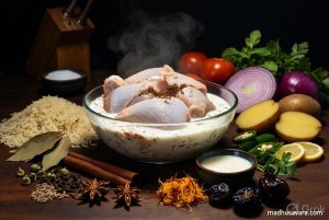 Vibrant arrangement of fresh Bombay Biryani ingredients including chicken, yoghurt, spices, basmati rice, onions, tomatoes, and herbs
