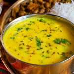 Authentic Mandyali Buttermilk Jhol served in a traditional brass bowl with steamed rice, the refreshing final course of a traditional Mandyali Dham from Himachal Pradesh.