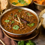 Authentic Kol Ka Khatta served in a traditional brass handi with steamed rice, showcasing the signature tangy horse gram curry of Himachali Mandyalli Dham, garnished with fresh coriander, ginger juliennes and whole red chilli,