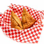 Authentic crispy Punjabi Samosa served in a paper basket, showcasing golden flaky pastry with a traditional potato filling, one of India's most popular street food snacks. Image courtesy: Halwai's – The Desi Chef.